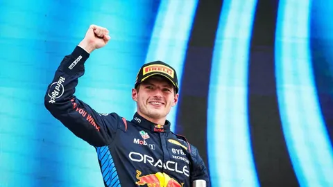 Max Verstappen u mornarsko plavom Red Bull odijelu podiže šaku u znak pobjede.