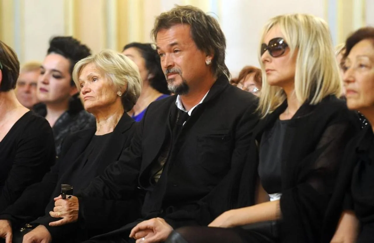 Gibonni i Sanja sa sunčanim naočalama sjede u publici na službenom događaju.