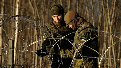 Dva vojnika u maskirnim uniformama postavljaju bodljikavu žicu na granici.