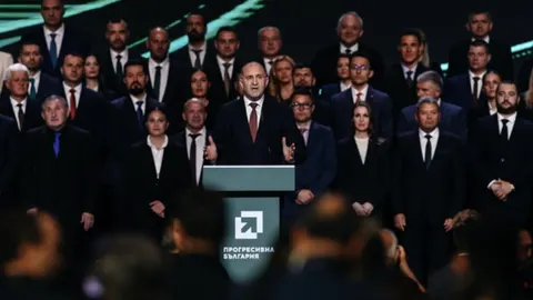 Rumen Radev govori za govornicom ispred skupine ljudi u odijelima.