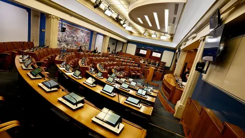 Prazna dvorana Skupštine Crne Gore s redovima klupa i monitorima.