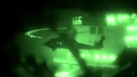 Zelena noćna snimka helikoptera iznad palube broda