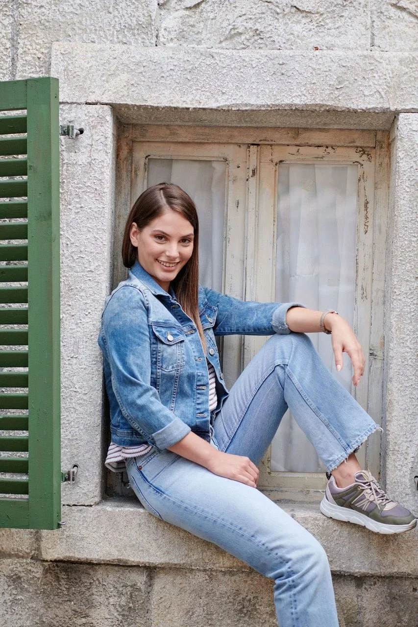 Mirna Mihelčić sjedi na kamenom prozoru u traper jakni i hlačama