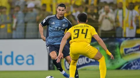 Cristiano Ronaldo vodi loptu na nogometnoj utakmici protiv protivničkog igrača.