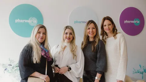 Četiri žene poziraju ispred Pharmeria logotipa na zidu.