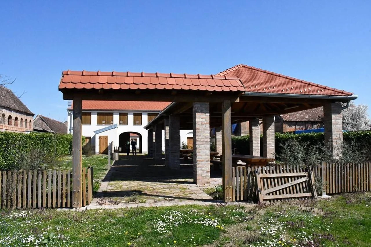 Natkriveni drveni trijem s klupama u uređenom dvorištu