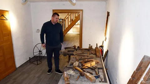 Muškarac promatra stare drvene alate u muzejskom prostoru