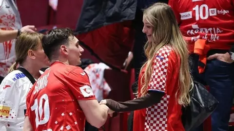 Josip Šimić u hrvatskom dresu drži za ruku suprugu Leonu na tribinama.