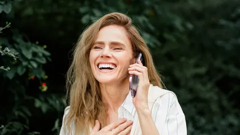 Nasmijana žena razgovara na mobitel na otvorenom