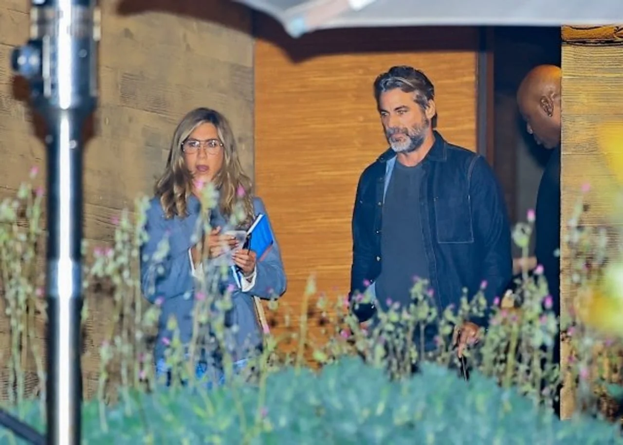 Jennifer Aniston s naočalama i Justin Theroux ispred drvenog zida