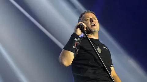 Marko Perković Thompson pjeva na pozornici pod jakim svjetlima reflektora