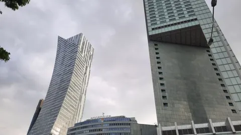 Moderni neboderi u Varšavi pod oblačnim nebom.
