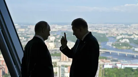 Siluete Vladimira Putina i ruskog dužnosnika ispred prozora s pogledom na grad.