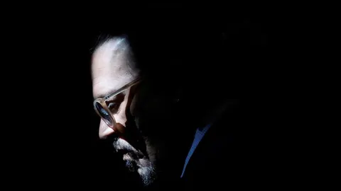 Profil portret Johnnyja Deppa s naočalama u polumraku