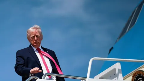 Donald Trump stoji na vrhu stepenica zrakoplova Air Force One pod vedrim nebom.