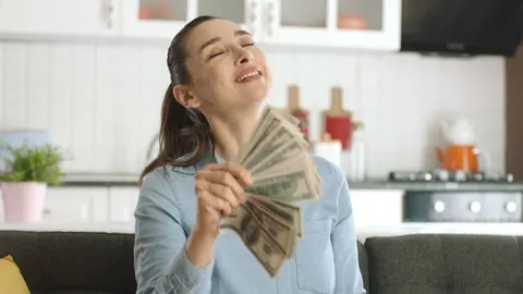 Nasmijana žena drži svežanj novčanica dolara u obliku lepeze