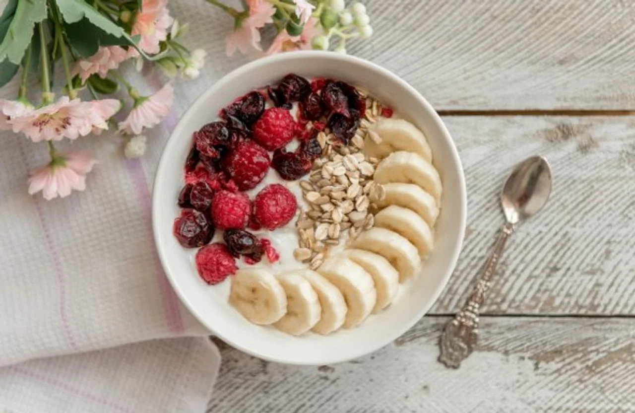 Bijela zdjelica sa zobenim pahuljicama, bananama i malinama