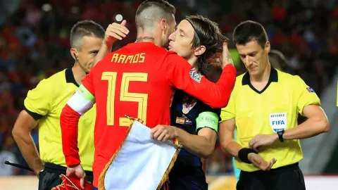 Sergio Ramos i Luka Modrić pozdravljaju se na nogometnom terenu uz suce u pozadini.