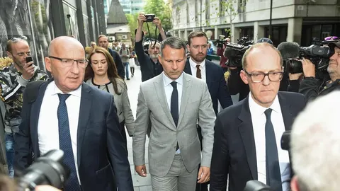 Ryan Giggs u sivom odijelu hoda okružen ljudima i novinarima