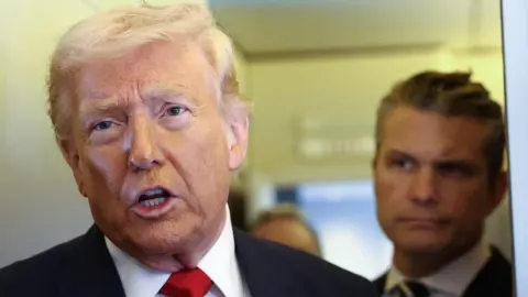 Donald Trump govori ispred novinara u pratnji suradnika