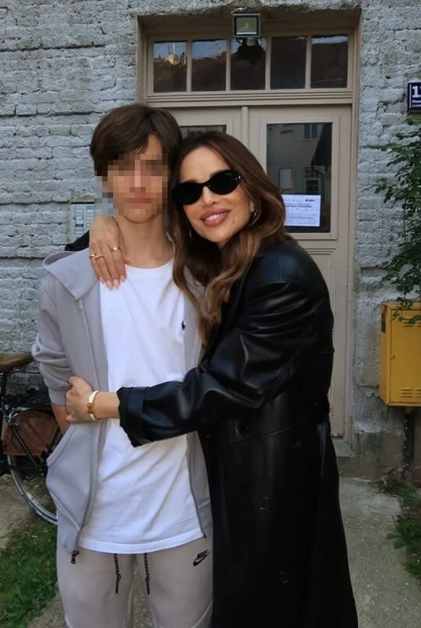 Severina u crnom kožnom kaputu grli sina Aleksandra ispred kamene kuće