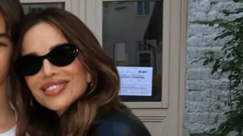 Severina s crnim sunčanim naočalama nasmijana ispred ulaza u zgradu