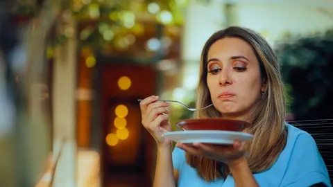 Žena sa sumnjom gleda u tanjur s hranom dok drži žlicu.