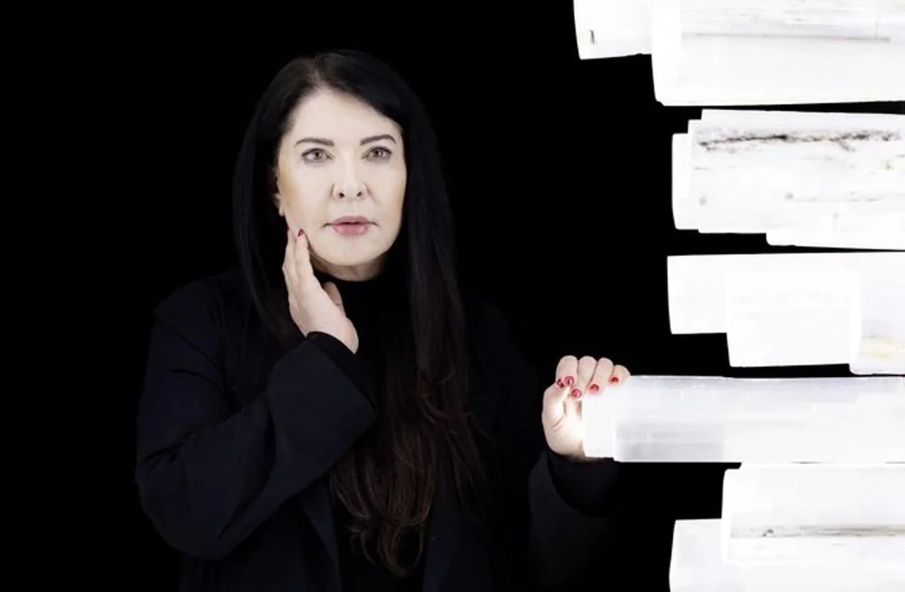 Marina Abramović pozira u crnom uz bijelu skulpturu od kristala.