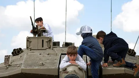 Djeca se igraju na vojnom tenku pod vedrim nebom