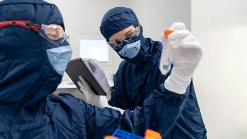 Znanstvenici u zaštitnim odijelima s maskama analiziraju laboratorijski uzorak