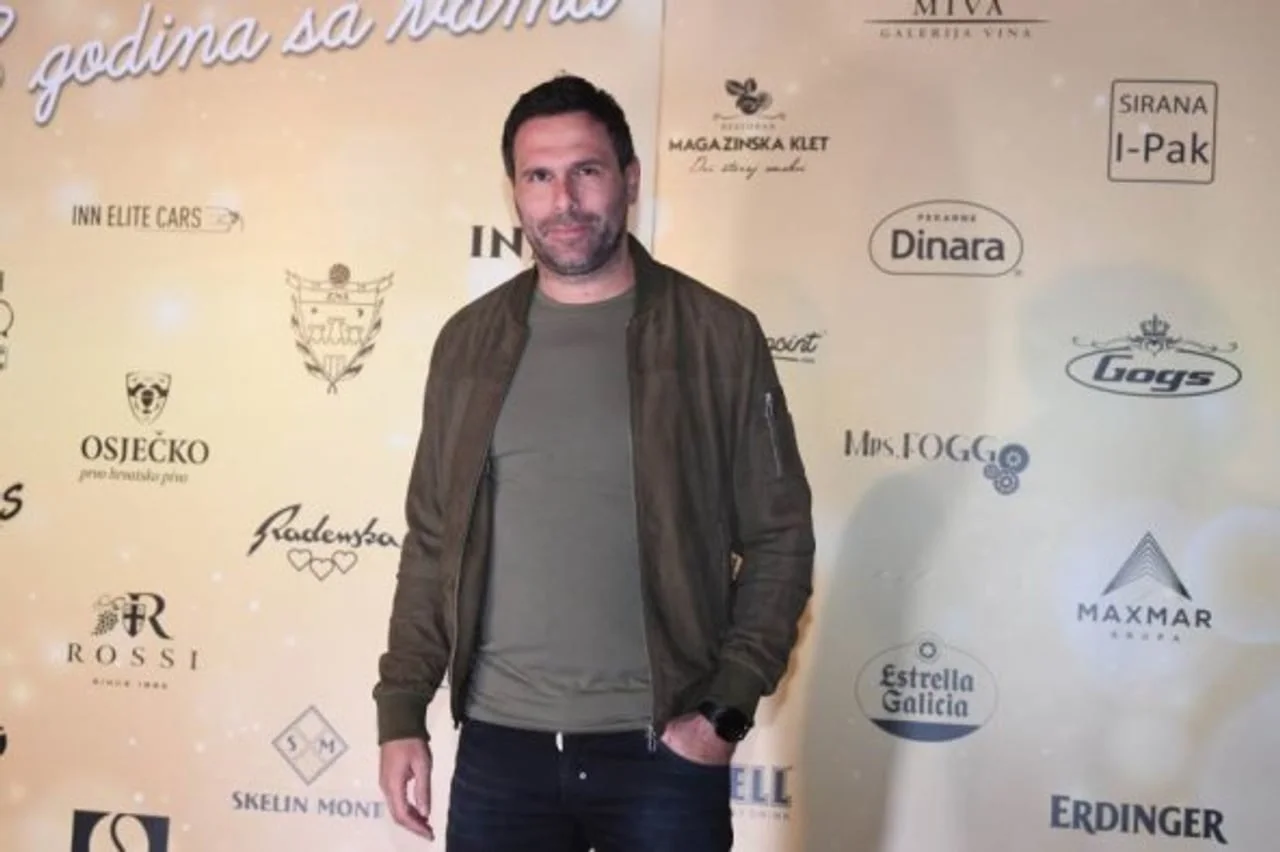 Jerko Leko u maslinastoj jakni stoji ispred zida s logotipima na javnom događanju.