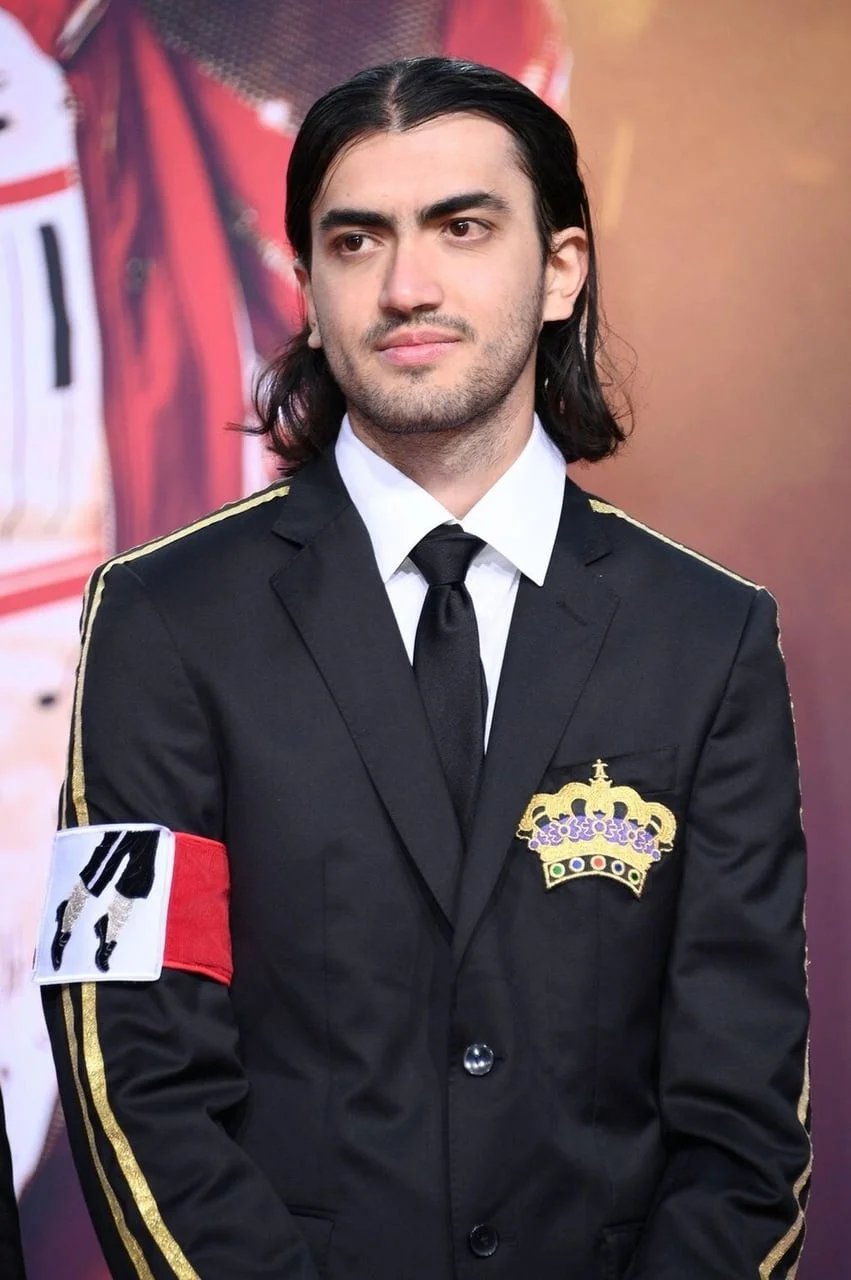 Portret Bigija Jacksona s dugom kosom u crnom odijelu sa zlatnim detaljima.