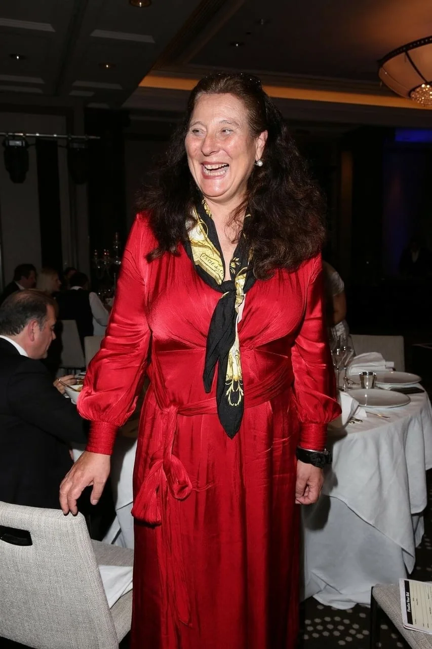 Žena u crvenoj haljini sa šalom smije se na večeri