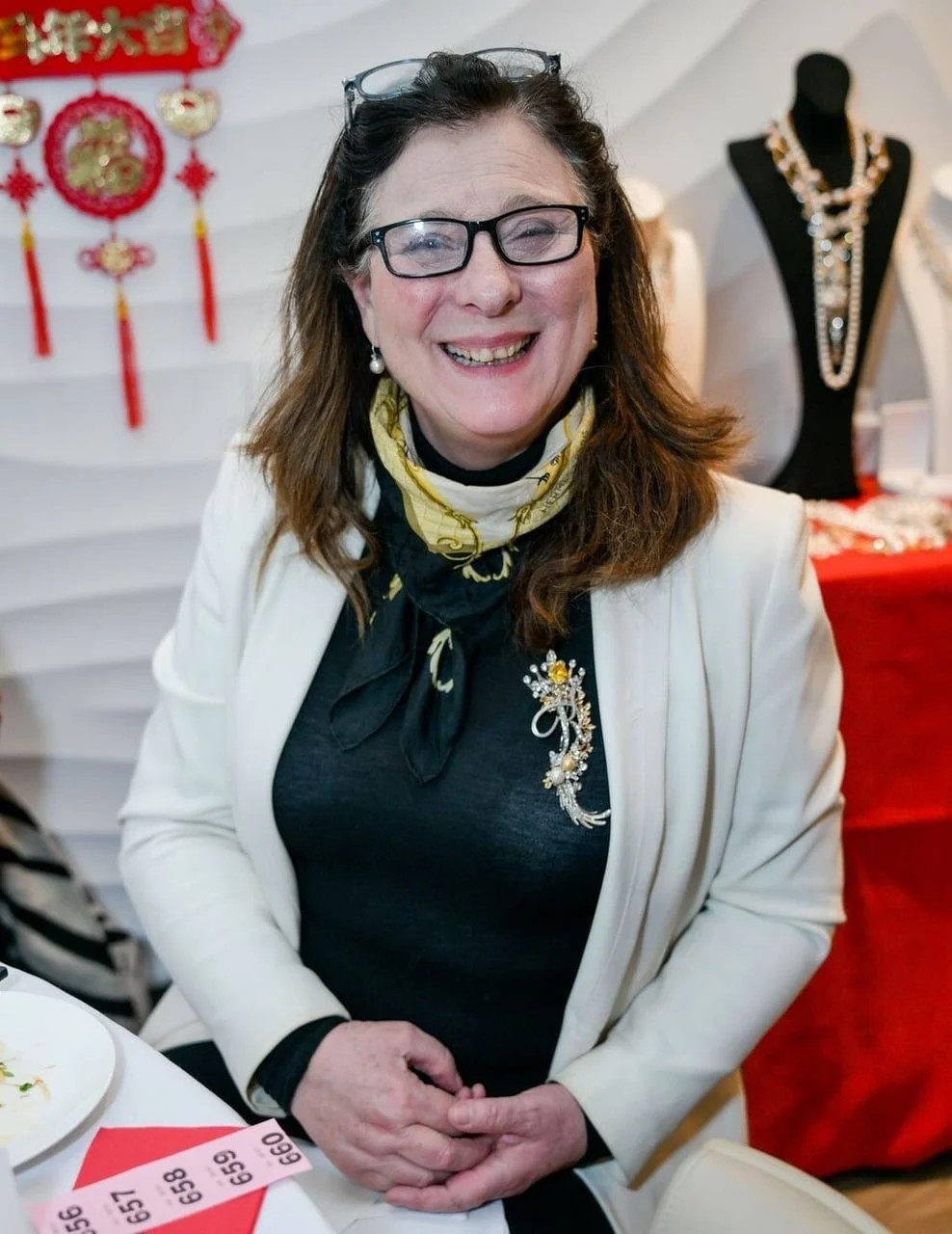 Žena s naočalama i u bijelom sakou sjedi za stolom