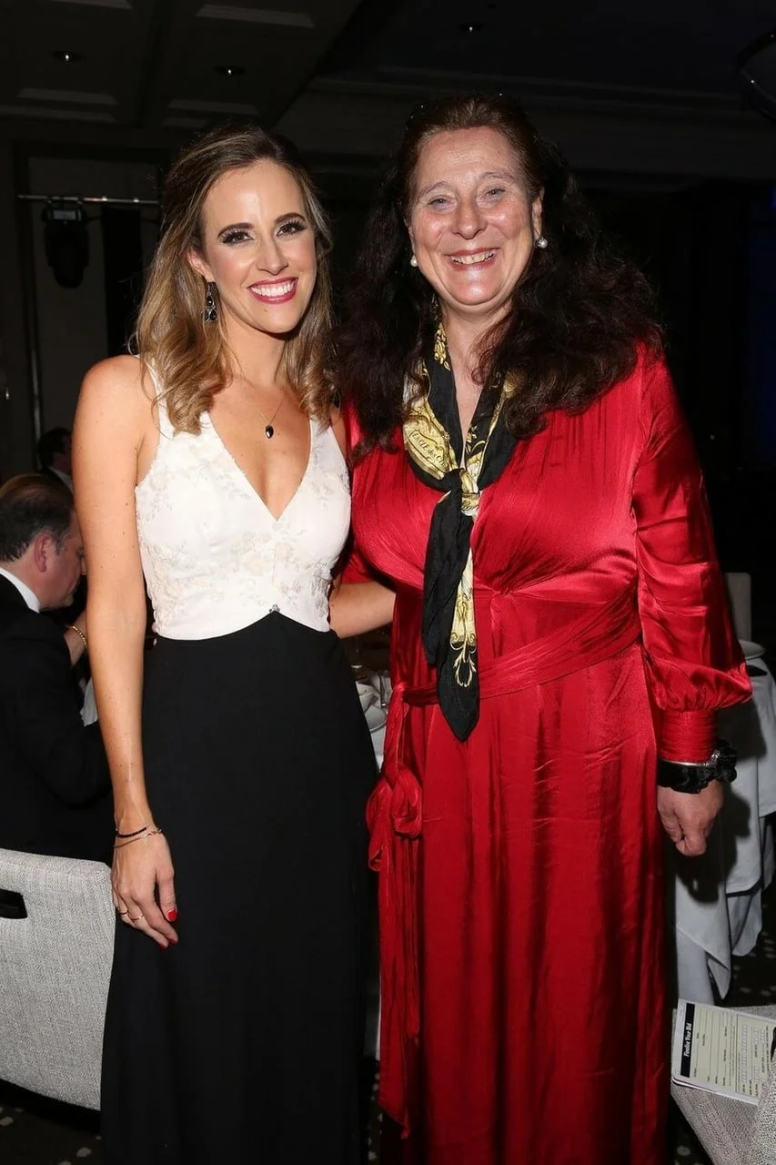 Dvije žene poziraju u svečanim haljinama na društvenom događaju