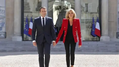 Emmanuel i Brigitte Macron drže se za ruke ispred Elizejske palače