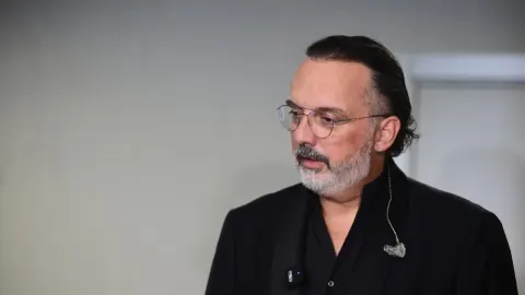 Pjevač Tony Cetinski u crnom odijelu s naočalama gleda u stranu