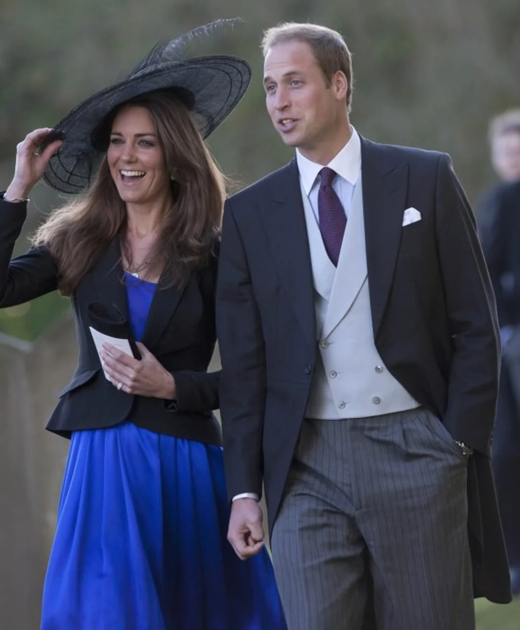 Kate Middleton s velikim šeširom smije se pored princa Williama na otvorenom.