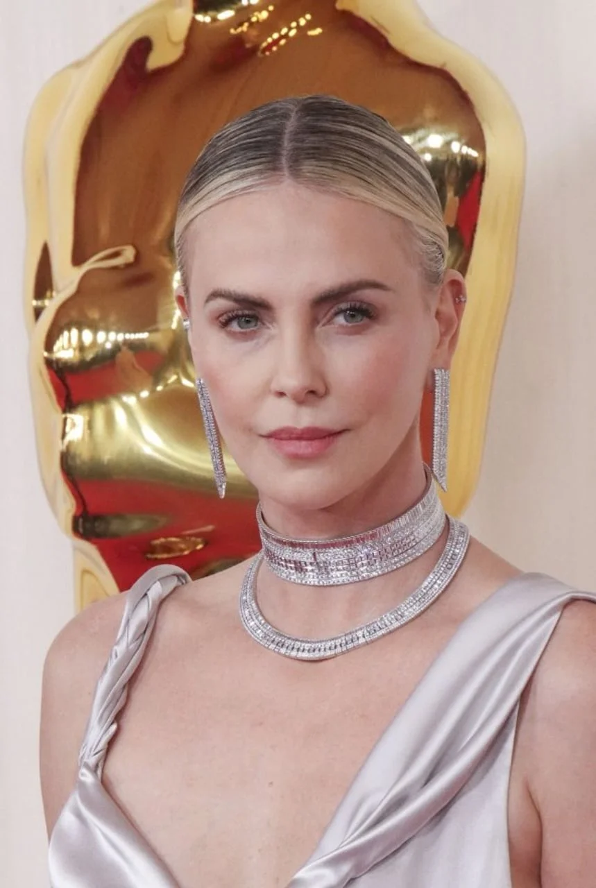 Portret Charlize Theron s elegantnom frizurom i raskošnim nakitom.