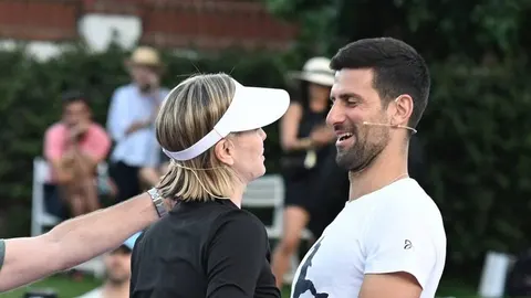 Charlize Theron i Novak Đoković razgovaraju na teniskom terenu.