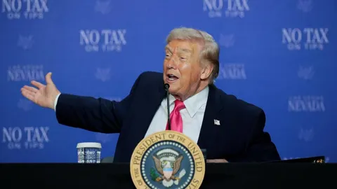 Donald Trump govori za govornicom s predsjedničkim pečatom na plavoj pozadini.