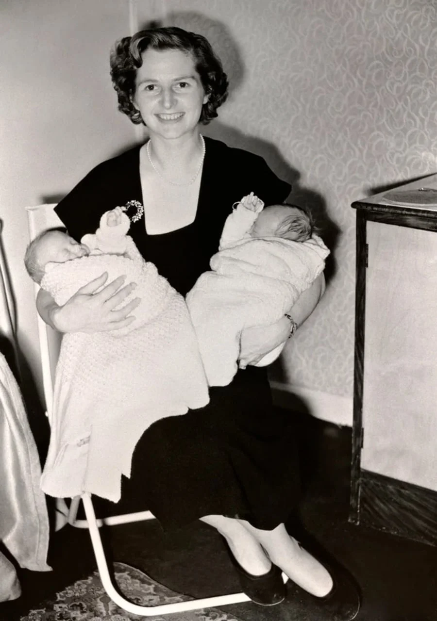 Mlada Margaret Tačer sjedi i drži dvije bebe u naručju