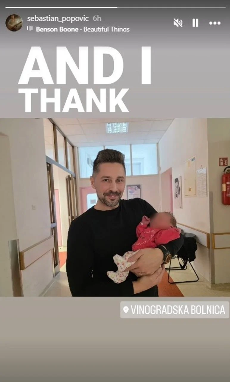 Sebastian Popović s osmijehom drži novorođenu kćer u bolničkom hodniku.