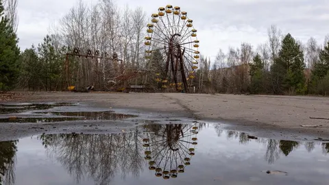 Napušteni panoramski kotač u Pripjatu s odrazom u lokvi vode.