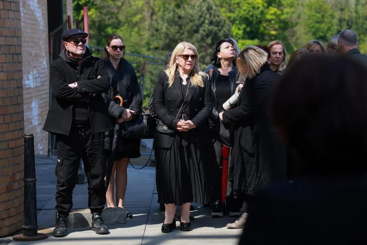 Posjetitelji na pogrebu u tamnoj odjeći i sa sunćanim naoćalama prate ceremoniju.