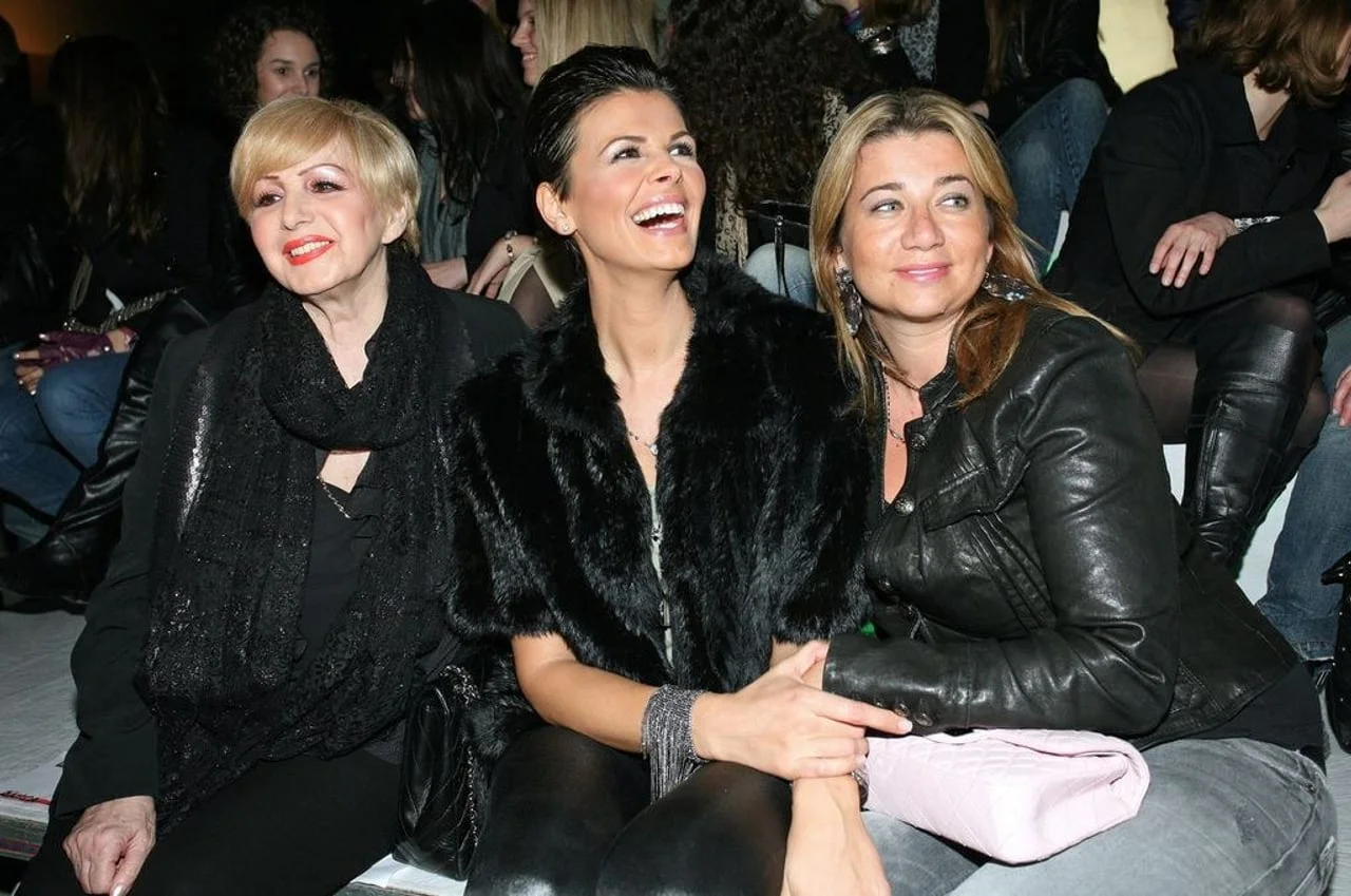 Tri ųene u svećanoj crnoj odjeći sjede i razgovaraju na modnom događaju.