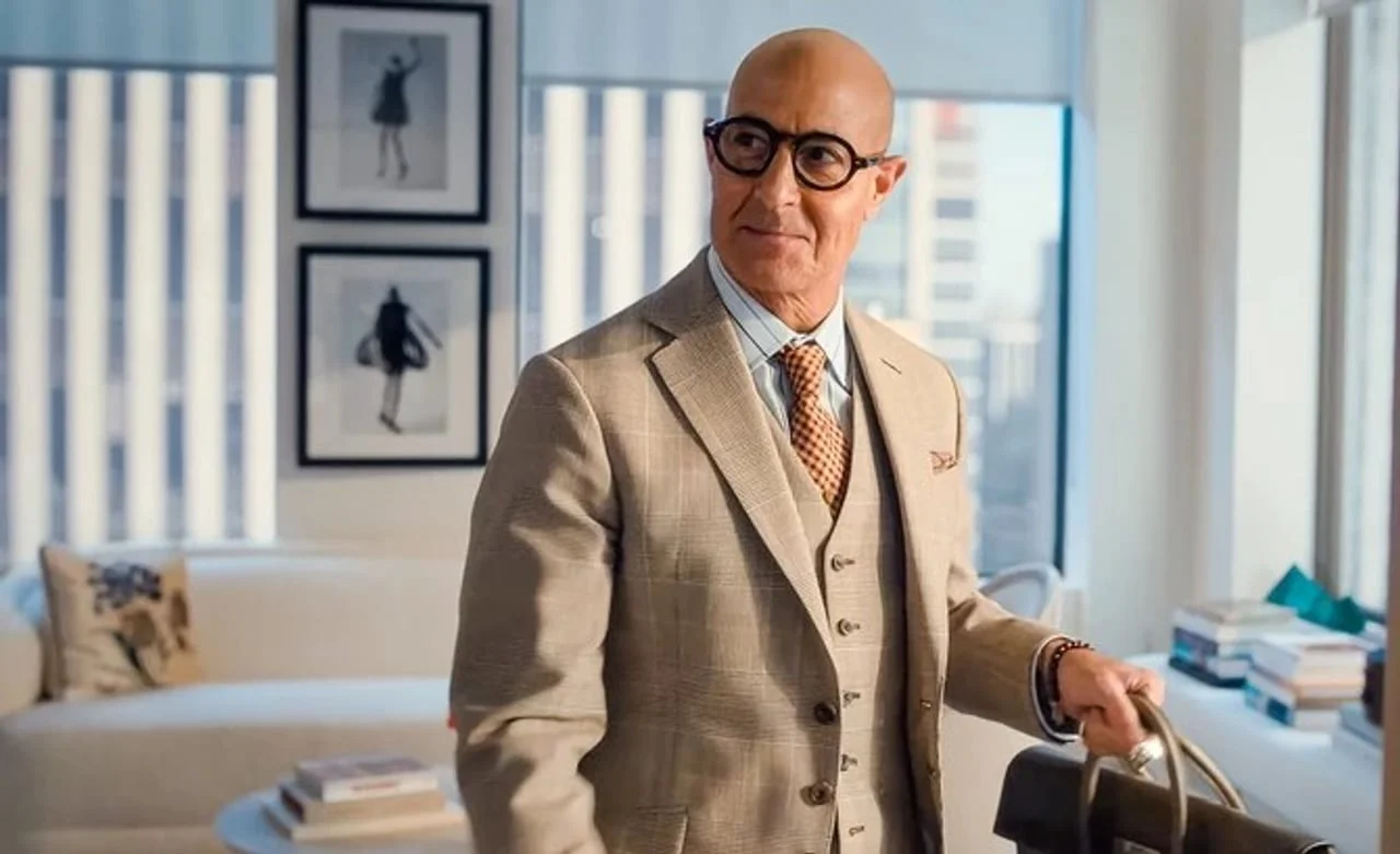 Stanley Tucci u elegantnom bež odijelu s torbom u modernom interijeru.