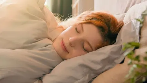 Žena mirno spava na mekanom jastuku pored prozora.