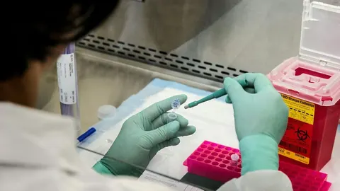 Znanstvenica u bijeloj kuti i rukavicama radi s uzorcima u laboratoriju.