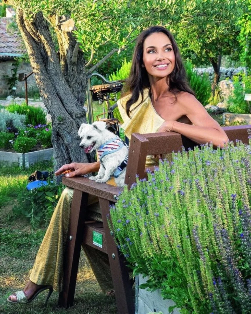 Fani Čapalija u zlatnoj haljini sjedi u vrtu sa svojim malim psom.